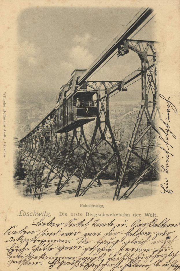 Ein altes Schwarz-Weiß-Foto einer Bahnbrücke mit einem Kran, umgeben von Bäumen und einem bewölkten Himmel, mit Text unten, der besagt: "Bahnstrecke, die erste Eisenbahnbrücke Deutschlands".