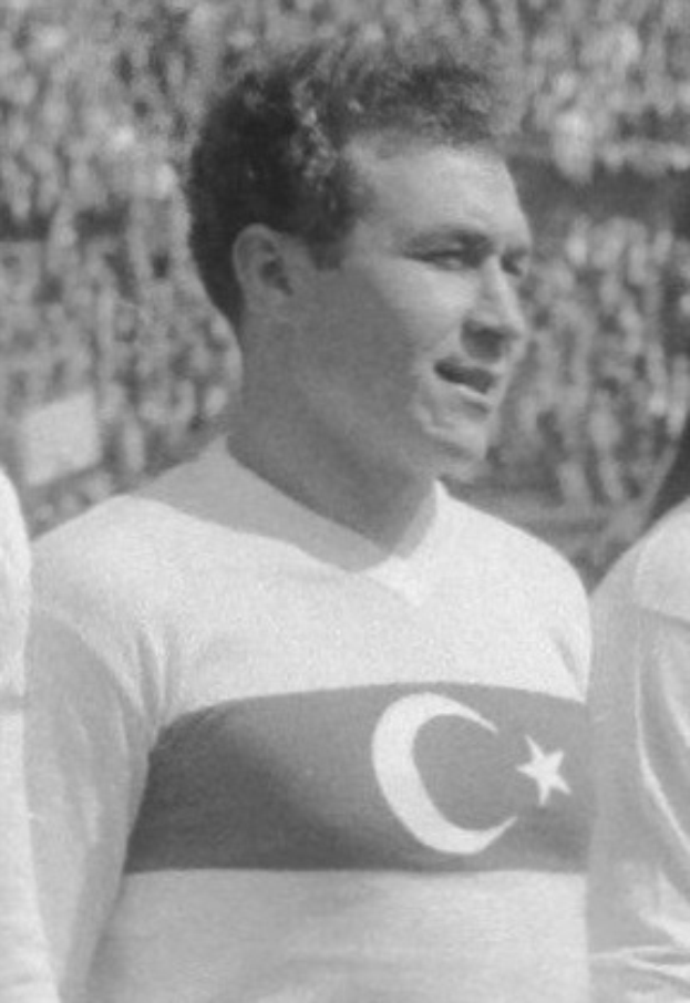 Ein Schwarz-Weiß-Foto eines Mannes, der neben einem anderen Mann steht, der ein weißes T-Shirt mit einer türkischen Flagge trägt, wobei der Mann in der Mitte als legendärer türkischer Fußballspieler identifiziert wird.