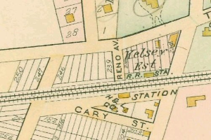 Alte Stadtkarte einer dicht bebauten Stadt mit nummerierten Parzellen, Textanmerkungen und einer "Grundstück-zu-Verkauf"-Anzeige unten.