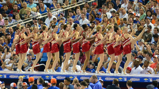Mädchen tanzen in der Mitte mit einer sitzenden Menge im Hintergrund.