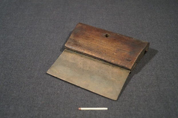 Kleiner hölzerner Streichholzschachtel mit offenem Deckel, enthaltend eine Zigarette, die auf einer schwarzen Oberfläche neben der Zigarette liegt.