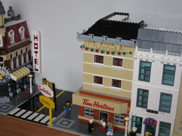 Spielzeuggebäude auf der rechten und linken Seite, ein Schild auf der linken Seite und kleine Spielzeuge am unteren Ende des Bildes.