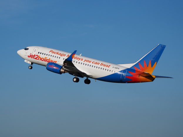 Ein Airbus A320-200 der Jet2holidays im Flug, mit einer weißen, blauen, orangen und roten Lackierung gegen einen blauen Himmel.