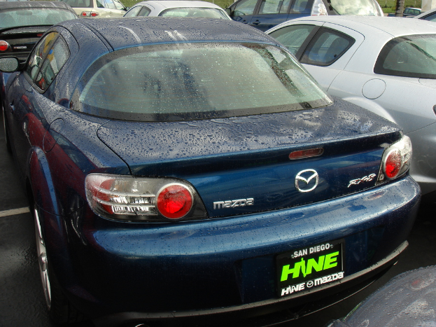 Mehrere Autos stehen auf einem Parkplatz mit einem Schild am unteren Rand des Bildes.