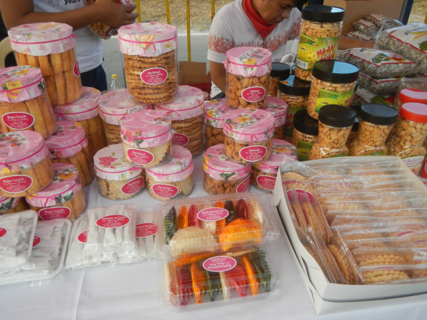 Eine Gruppe von Menschen, die um einen Tisch mit verschiedenen Lebensmitteln stehen.