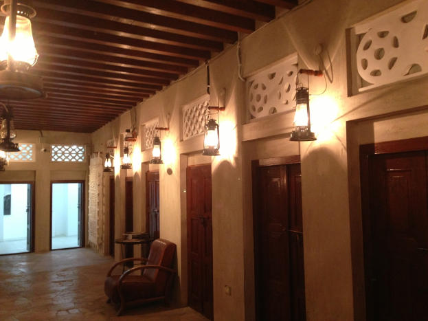 Ein Gebäude mit geschlossenen Räumen, jeweils mit einer wandmontierten Lampe und einem Deckenventilator, einem Stuhl davor und zwei Eingängen, sowie zusätzlichen Lampen an der Decke.