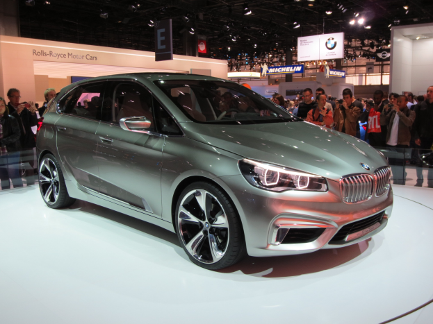 BMW 2er Active Tourer Concept auf der IAA in Frankfurt ausgestellt, mit Besuchern, die es unter Deckenleuchten und Texttafeln im Hintergrund fotografieren.
