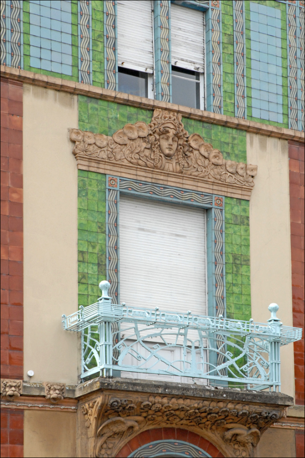 Ein an einer Wand angebrachtes Dach mit zwei Fenstern und einer Jalousie oben sowie einem Gebäude auf der rechten Seite.
