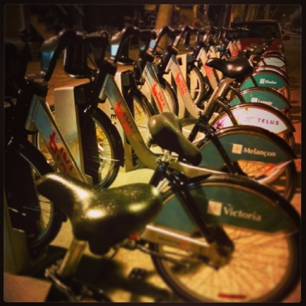 Mehrere Fahrräder sind in der Mitte des Bildes geparkt, dahinter ist ein Fahrzeug zu sehen.