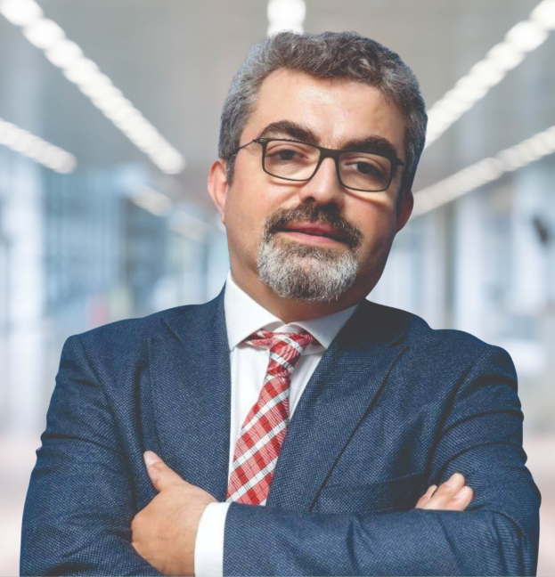 Ein Mann im Anzug und Krawatte mit verschränkten Armen, der eine Brille trägt und vor einem unscharfen Hintergrund steht, mit Text, der ihn als neu ernannten Marketingchef identifiziert.