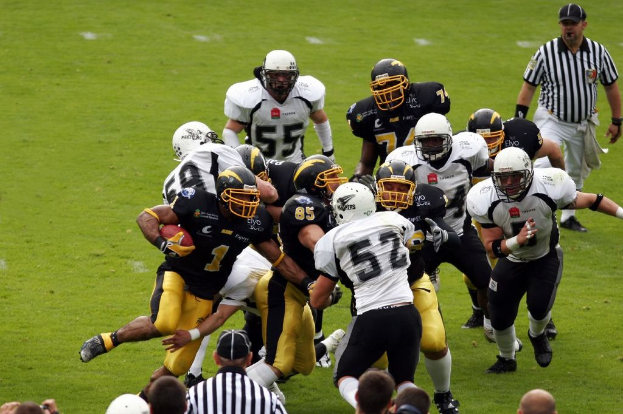 Menschen mit Helmen spielen ein Spiel auf einem grünen Feld.