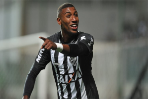 Fußballspieler in schwarzer und weißer gestreifter Jerseys mit strahlendem Lächeln beim Feiern eines Tors, Hintergrund unscharf.