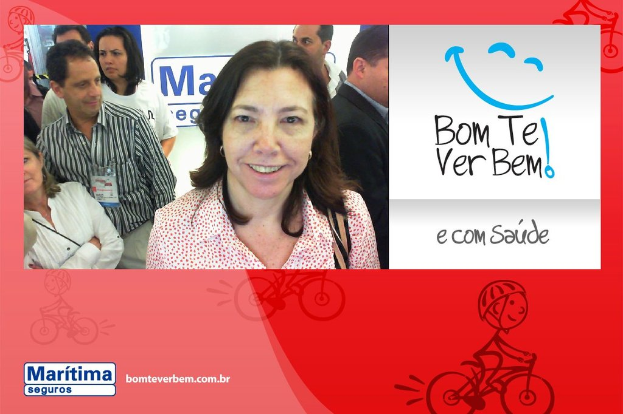 Eine Frau, die im Vordergrund steht und lächelt, mit Menschen im Hintergrund, Text und ein Cartoon-Emoji oben rechts und eine Cartoon-Person, die unten fährt.