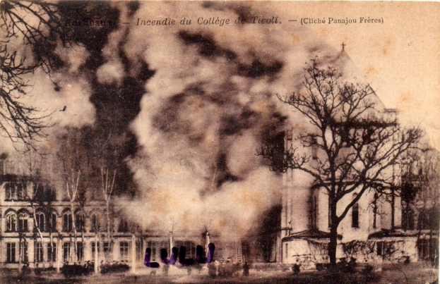 Schwarz-weiß-Foto eines brennenden Gebäudes mit Rauch, der aus den Fenstern quillt, umgeben von Bäumen und teilweise verdecktem Text oben.