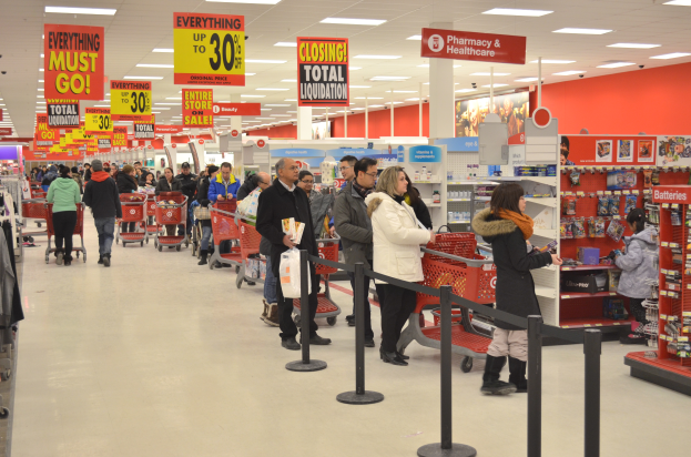 Ein volles Walmart-Geschäft mit Einkaufstüten tragenden Kunden und Einkaufswagen, mit verschiedenen Ladeneinrichtungsgegenständen, Schildern und Deckenleuchten im Hintergrund.