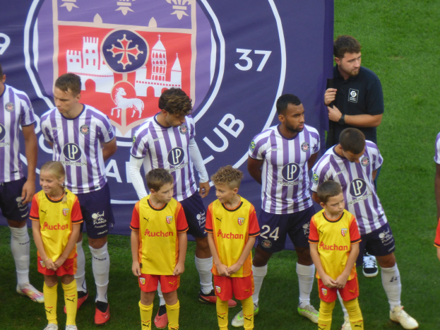 Eine Gruppe junger Fußballspieler in Chivas-de-Guadalajara-Trikots, die auf einem Feld mit einem Teambanner im Hintergrund stehen.