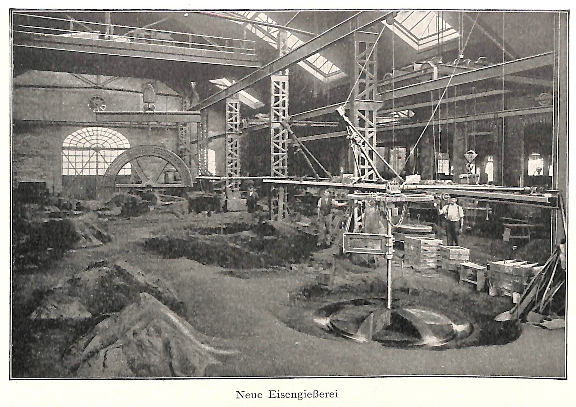 Ein altes Schwarz-Weiß-Foto einer Fabrik mit Arbeitern, die eine Maschine bedienen, umgeben von Metallstangen und -pfählen, mit dem Text "Neue Eisenglebeerei, die erste Fabrik in Deutschland" unten.