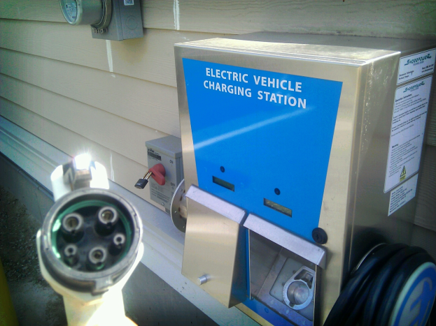 Eine Ladestation für Elektrofahrzeuge mit einem daran befestigten Kabel, das an der Seite eines Gebäudes montiert ist.