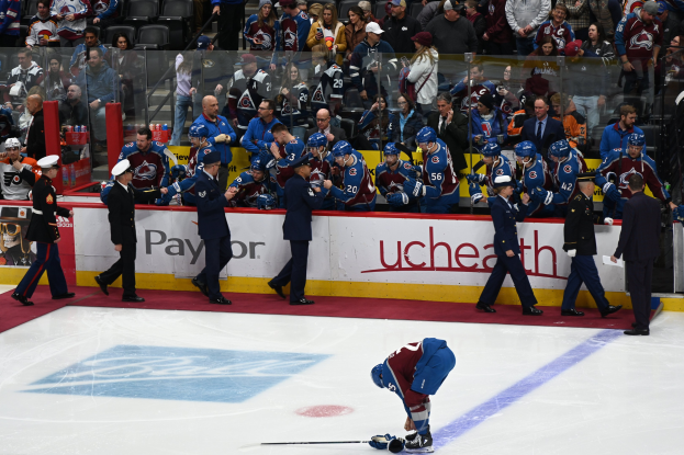 Eishockeyspieler auf dem Eis umgeben von Teamkollegen und Gegenspielern, mit Zuschauern im Hintergrund während eines NHL-Spiels zwischen Colorado Avalanche und San Jose Sharks am 24. März 2015.