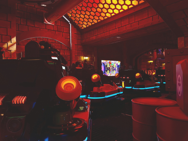Ein hell erleuchteter Raum voller verschiedener Arcade-Videospielautomaten und -bildschirme, mit einer Decke mit Einbaulampen.