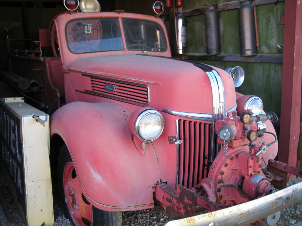 Ein Kraftfahrzeug steht auf einem steinbedeckten Boden, mit Feuerlöschern an der Wand daneben.