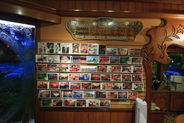 Ein Holzbrett mit Text, Fotos und einem Schrank mit Boxen, einer Papiertüte, einem Turmventilator und einer Holzschnitzerei.