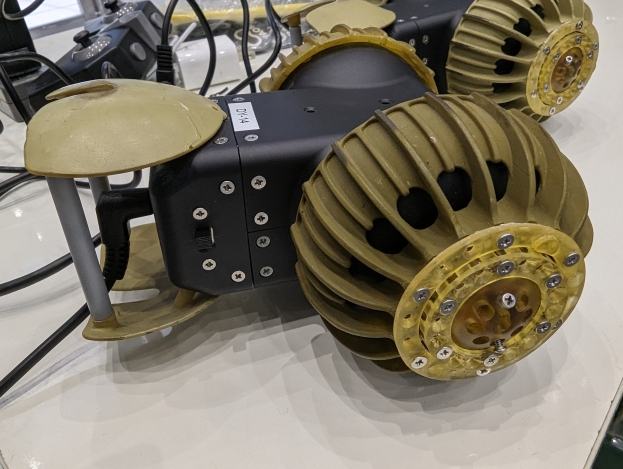 Nahaufnahme eines schlanken, metallischen 3D-gedruckten Robotik-Bauteils auf einem Tisch umgeben von Kabeln.