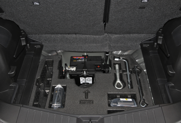 Das Kofferraumdeckel eines Autos ist offen und zeigt eine Sammlung von Werkzeugen und verschiedenen Gegenständen im Inneren.