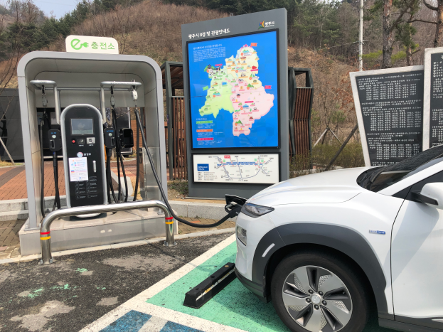 Ein Elektroauto lädt an einer Station in Seoul, Südkorea, umgeben von Bäumen mit dem Himmel im Hintergrund.