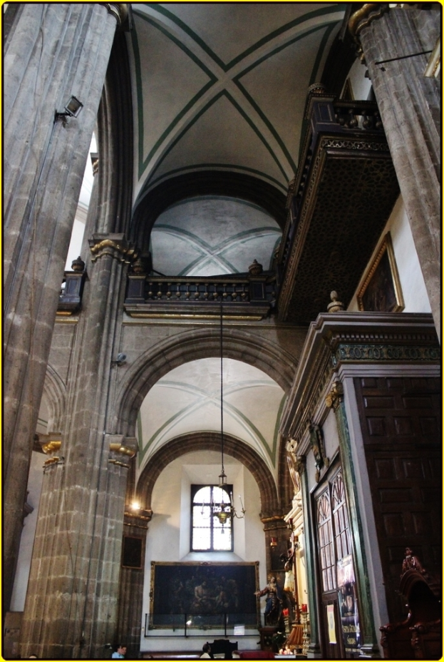 Ein Innenblick in einen Palast mit Schränken, beleuchteten Säulen, Wandskulpturen, einem großen Foto Rahmen und einer herabhängenden Lampe von der Decke.