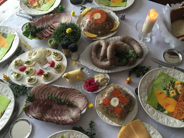 Ein traditioneller deutscher Ostertisch mit verschiedenen Gerichten, Besteck, Gläsern, Kerzen und Stühlen.