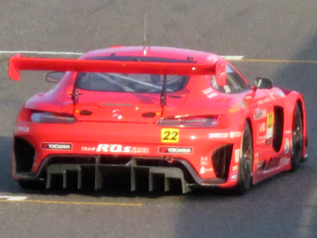 Ein leuchtend roter Porsche 911 GTS Rennauto mit einer großen Heckspoiler und Flügel, der auf einer Rennstrecke fährt.