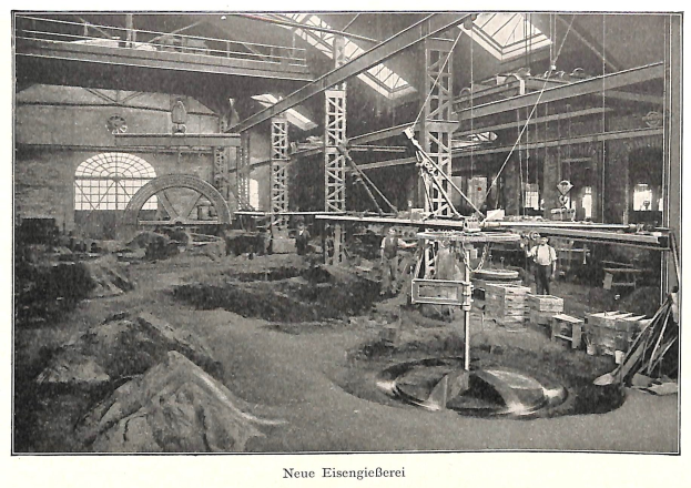 Schwarzes und weißes Foto eines Fabrikinneren mit Arbeitern, die Maschinen bedienen, Metallstangen und -stangen sowie die Beschriftung "Neue Eisengießerei, die erste Fabrik Deutschlands" unten.