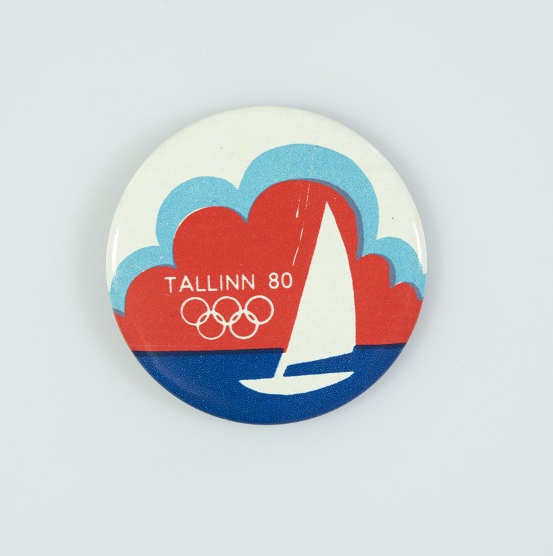 Gedenkmünze zum 80. Jubiläum der Olympischen Spiele in Tallinn, die ein Segelboot und den Text 'Tallinn 80 Olympische Spiele' auf einem weißen Hintergrund zeigt.