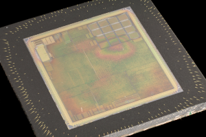 Nahaufnahme eines rechteckigen Halbleiterchips mit metallischem Glanz, schmalem Metallrahmen und kleinen Kantenl├Âchern auf schwarzem Hintergrund, mit leicht erh├Âhten Kanten.