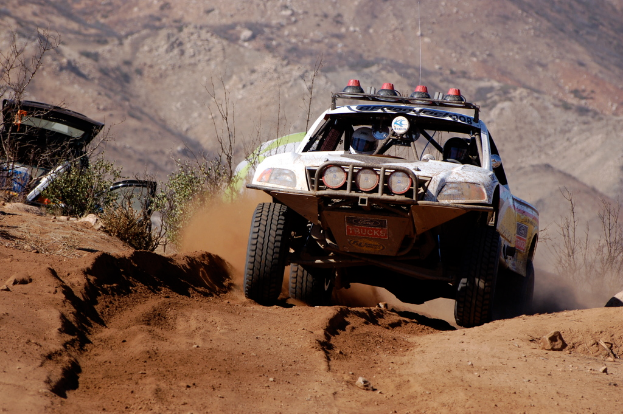Ein Plakat mit Fahrzeugen, einem Gebäude, einem Pfahl, einer Flagge, einer Fahne und einem bewölkten Himmel.
