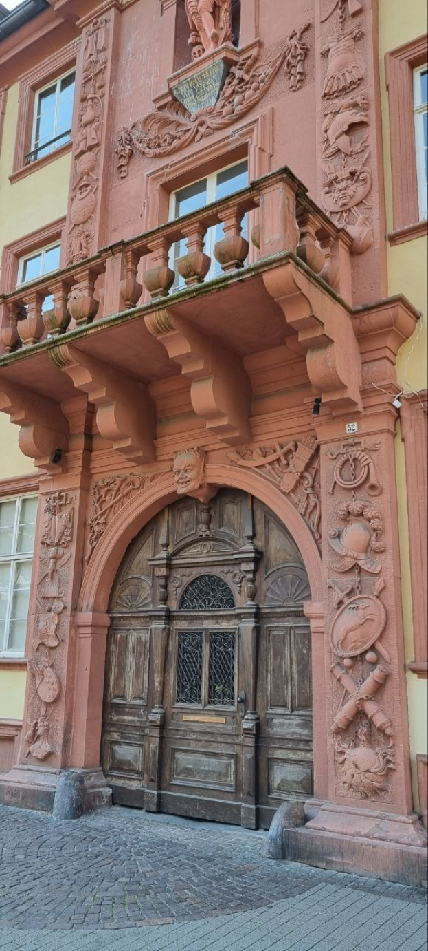 Altes Gebäude in Heidelbergs Altstad mit hölzerner Tür, Fenstern und detaillierten Fassadenverzierungen.
